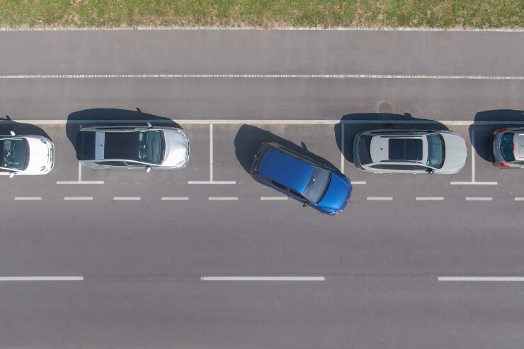 Aerial view of a blue car parallel parking along a road