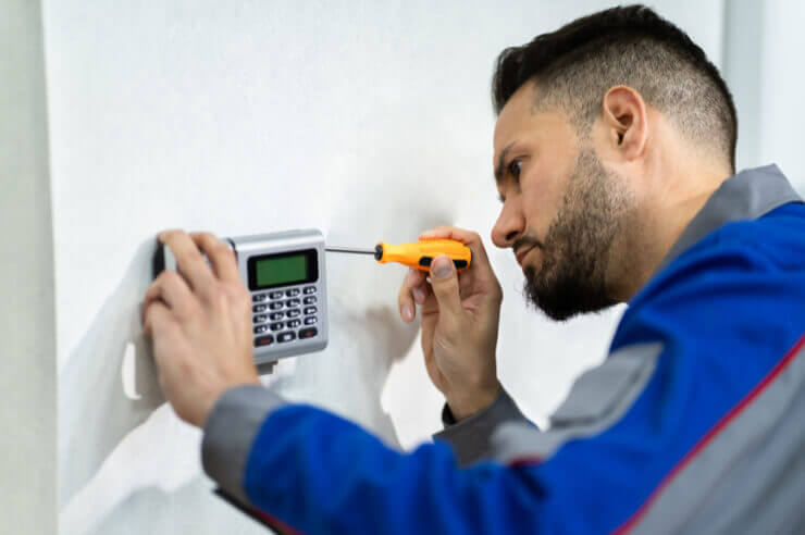Man installing home alarm system using orange screwdriver