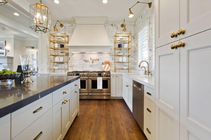 Large white kitchen with cabinets and drawers fitted with gold hardware