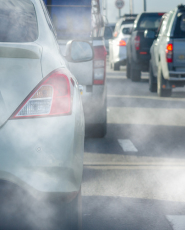 Cars on a road with exhaust fumes being emitted