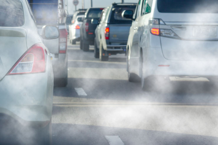 Cars on a road with exhaust fumes being emitted