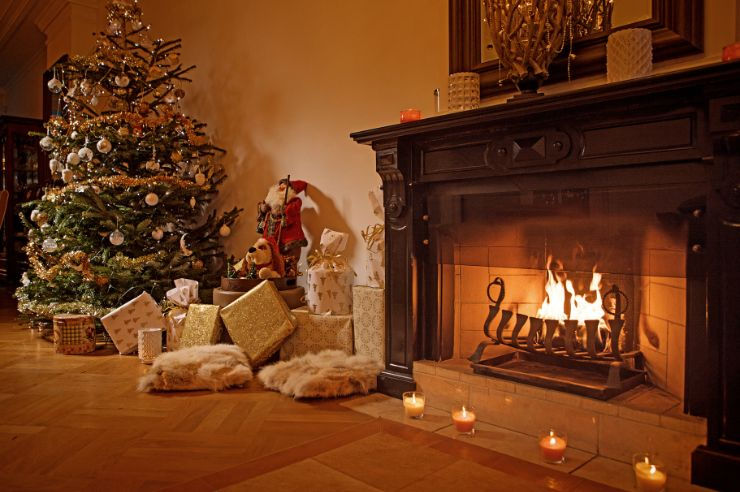 Christmas tree and presents next to a lit fireplace