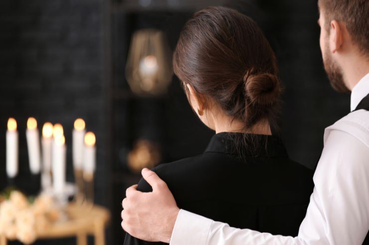 Couple from behind standing close to candles wearing black clothes