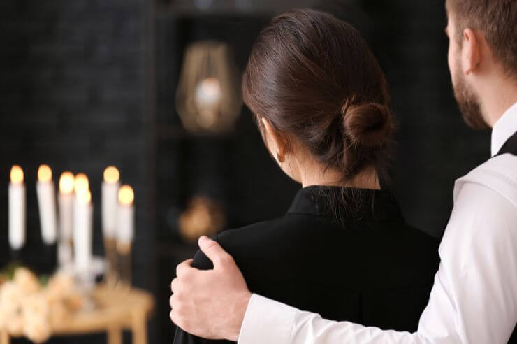 Couple grieving Couple from behind standing close to candles wearing black clothes