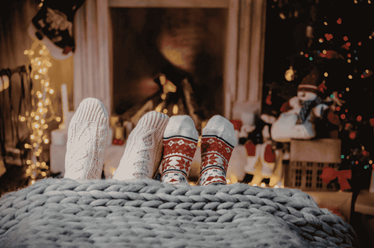Two people resting on a sofa, their feet stick out of the bottom of their blanket