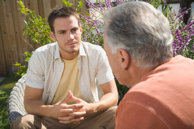 Two men sitting in a garden having a conversation
