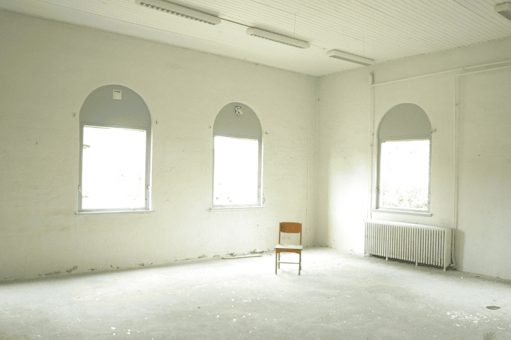 empty old house Wide, empty room with three bright windows and a wooden chair