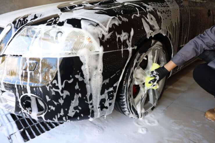 Car Exterior getting washed Front view of black car, being handwashed with soap and sponge