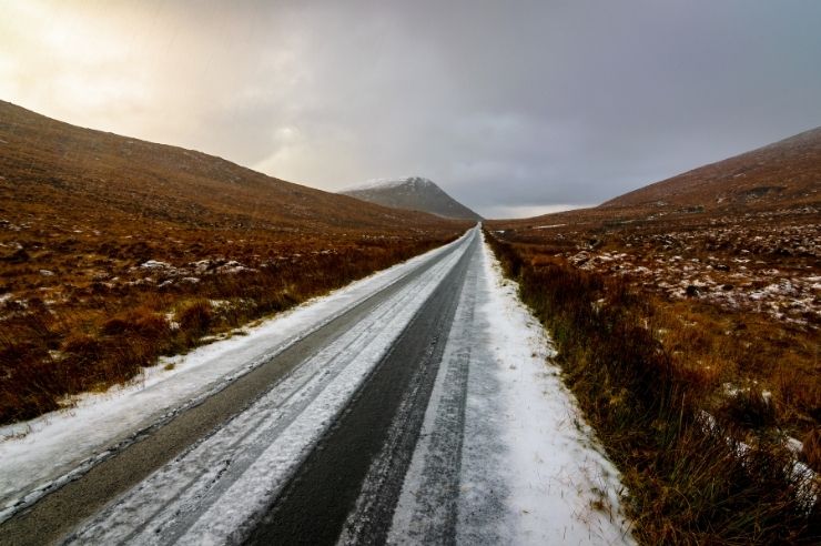 Icy road conditions in Ireland Long road during winter conditions, mountains either side