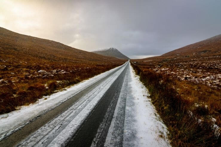 Icy road conditions in Ireland Long road during winter conditions, mountains either side