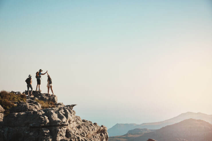 Live purposefully Three hikers at the top of a mountain looking out at the view on a sunny day