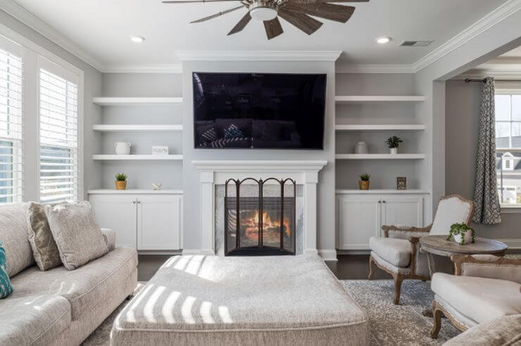 Light coloured living room with sofa, ottoman and an open fire