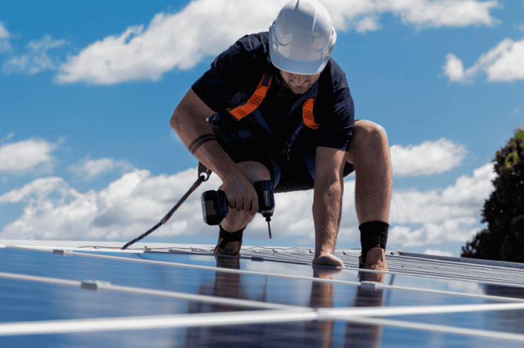 Man installing solar panels Workman installing solar panels wearing a white hard hat and hi-vis vest