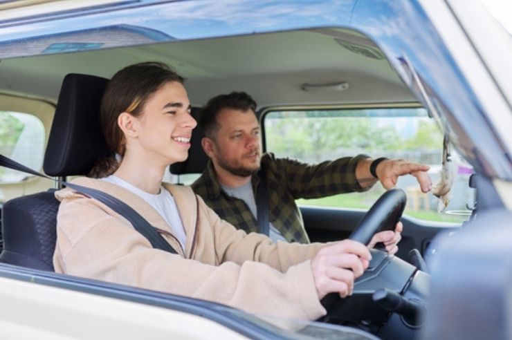 2.	Teenage driver smiling at the wheel while an older man in the passenger seat points ahead.