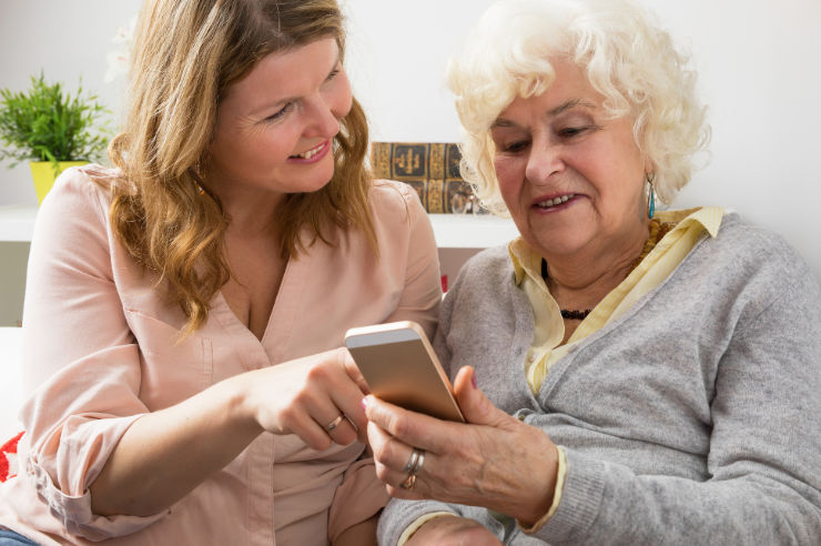 Woman showing an elderly woman something on a smartphone
