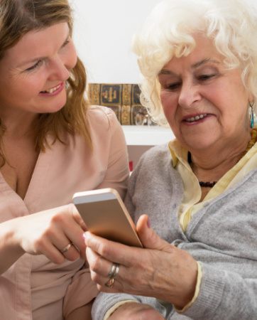 Woman showing an elderly woman something on a smartphone