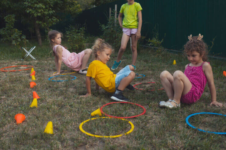 Kids play in the garden with an obstacle course Four children playing outdoors with hula hoop rings