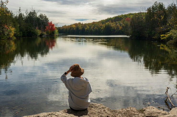 Quiet Reflection Woman sitting alone at lake wearing a hat
