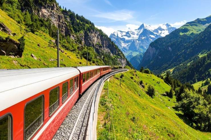 Red Train driving up through the Alps Red train driving through the Swiss Alps on a clear, sunny day