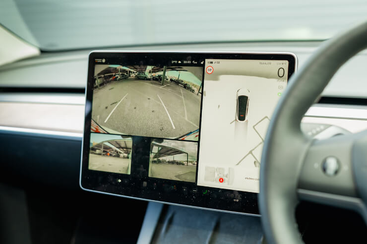 Interior view of a car’s dashboard with larger screen showing parking assistance tool