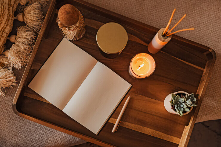 Blank journal resting on side table with diffuser and lit candle