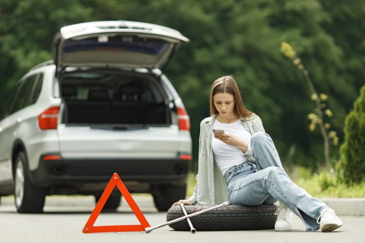 Woman sitting on tire looking at phone