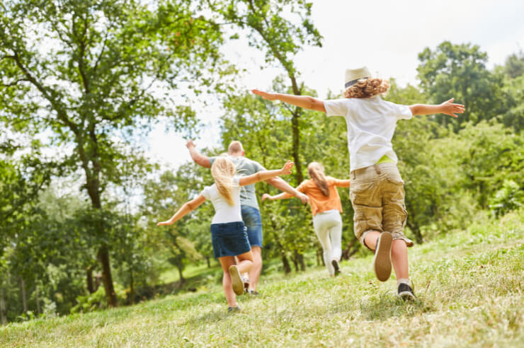 family playing in a field together two children and two adults playing chase in a green field