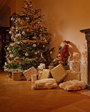 Christmas tree and presents next to a lit fireplace