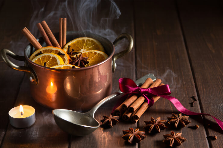 Simmer Pot Festive simmer pot with oranges and cinnamon, a ladle and lit candle rest nearby