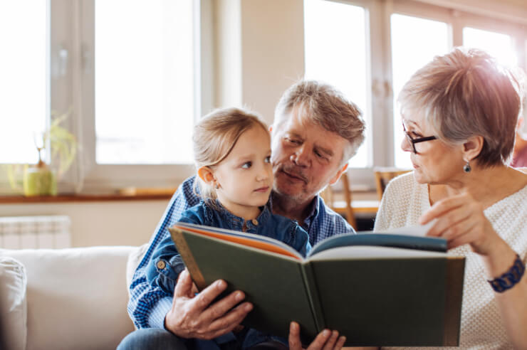Older couple reading book to young girl