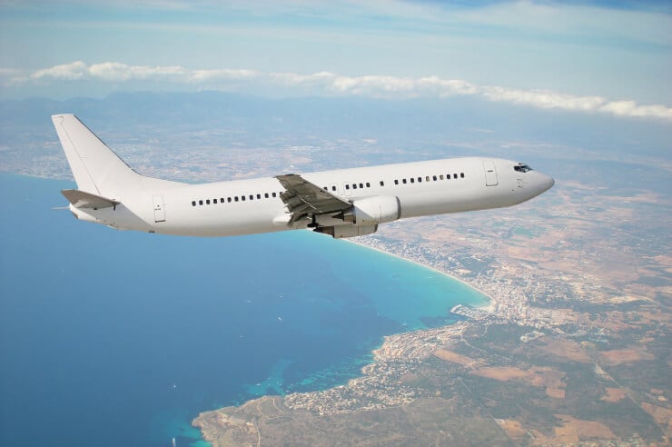White airplane flying over the coastline above the ocean