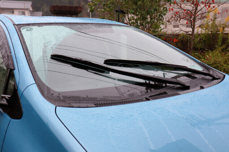 Blue car pictured from the front, wipers in motion during the rain