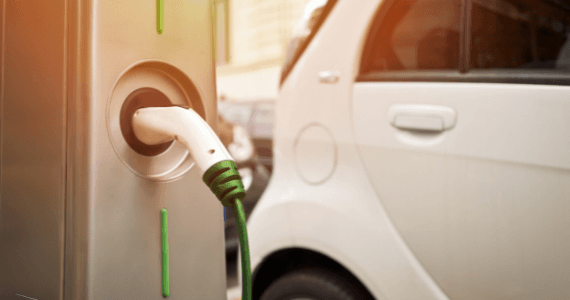 Close-up of an electric vehicle being charged at a public charging station.