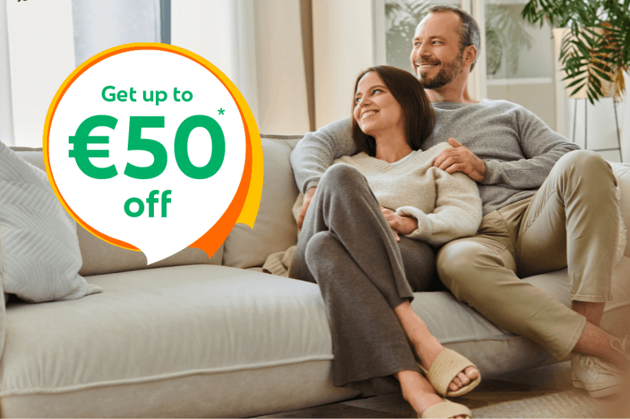 Couple relaxing together on a sofa at home with text overlay “Get up to €50 off”, promoting home insurance savings in Ireland.
